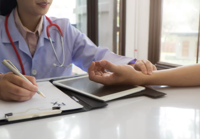 Provider monitoring patient’s pulse and documenting health status using a tablet.
