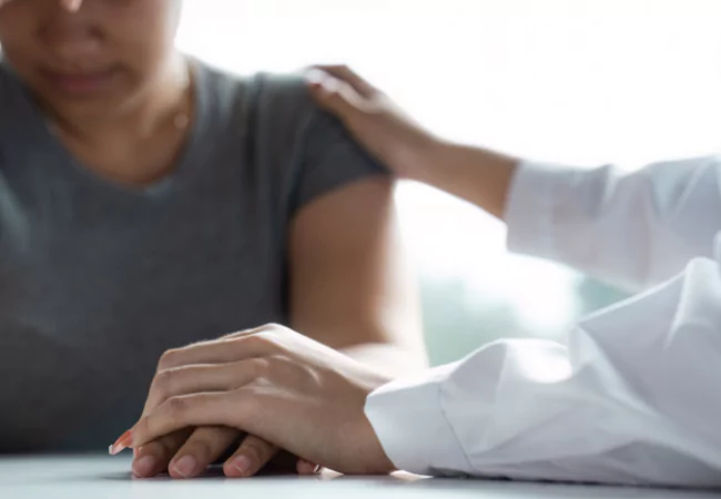 Doctor supporting patient while filling out FMLA medical leave paperwork.